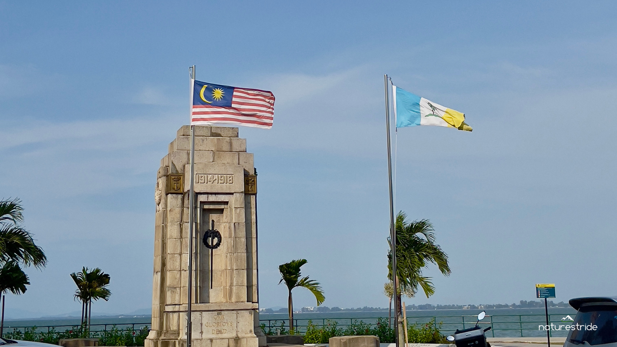 A monument with a flagpole stands proudly beside a motorcycle in Georgetown, Penang, Malaysia.